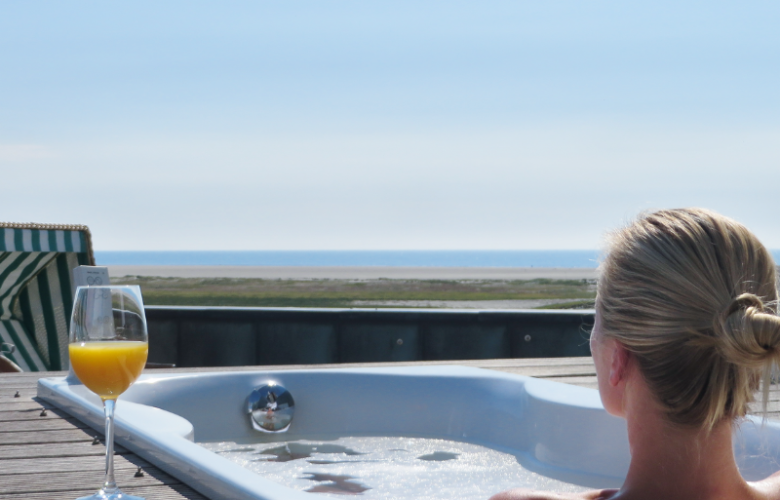 Frau badet auf Außenterrasse im Whirlpool mit Blick auf das Meer